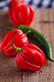 Closeup of red and green chili peppers on wooden board surface