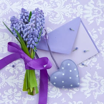 Small envelope and a small bouquet of hyacinths on purple