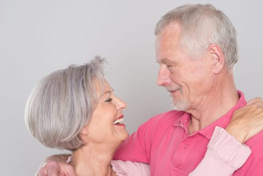 Happy senior couple against a grey background