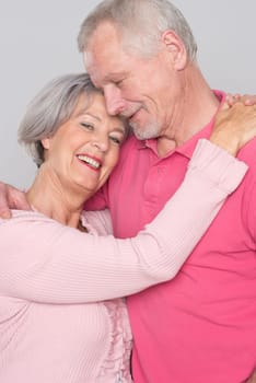 Happy senior couple against a grey background