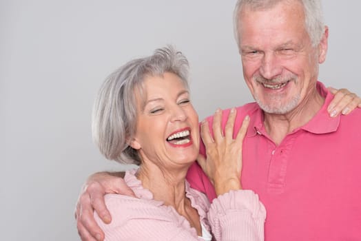 Happy senior couple against a grey background