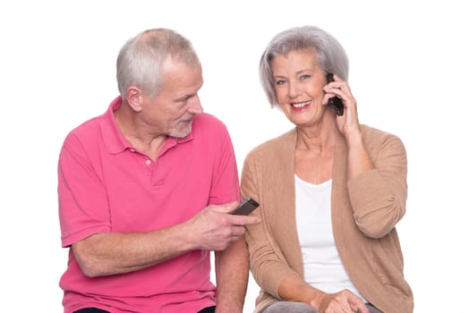 Senior couple with smartphone against a white background