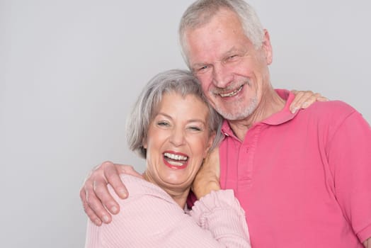 Happy senior couple against a grey background