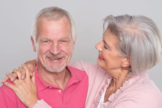 Happy senior couple against a grey background
