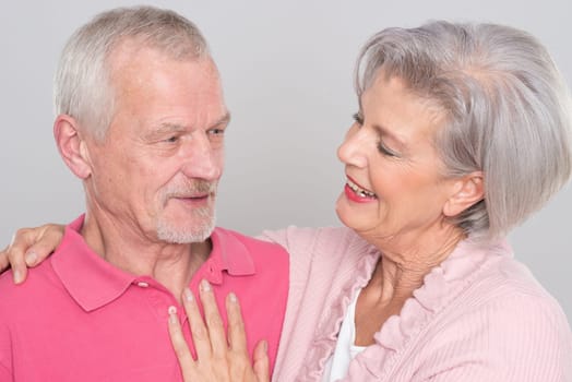 Happy senior couple against a grey background