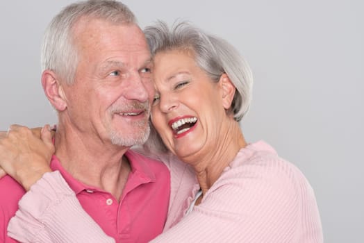 Happy senior couple against a grey background