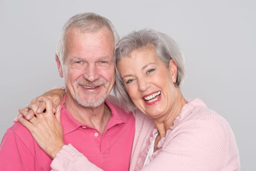 Happy senior couple against a grey background