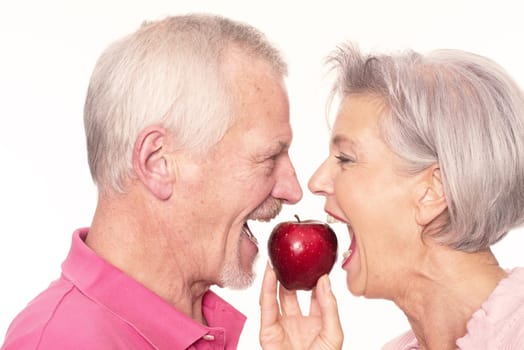 Senior couple with an apple against a white background