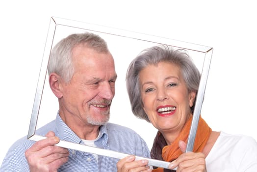 Elderly couple sees through a picture frame against a white background