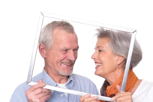 Elderly couple sees through a picture frame against a white background