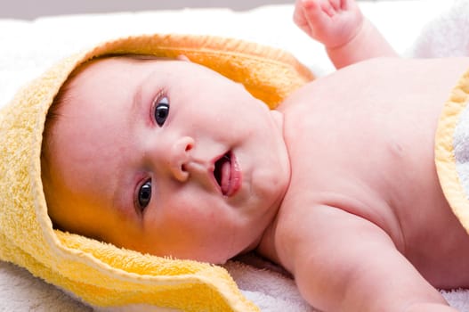 Sweet newborn baby wrapped in a towel and smiling, isolated against a white background.