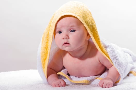 Sweet newborn baby wrapped in a towel and smiling, isolated against a white background.