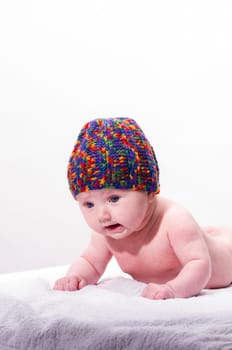 Sweet newborn baby wearing a colorful woolen cap and smiling, isolated against a white background.