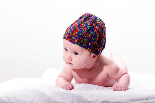 Sweet newborn baby wearing a colorful woolen cap and smiling, isolated against a white background.