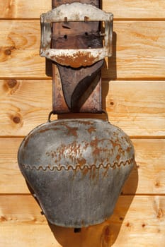 Very old cowbell hangs on wooden hut