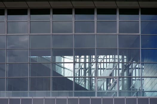 The photograph of a modern house facade with a staircase behind glass.