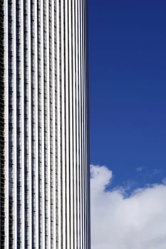 The photograph of a high-rise facade in the backlight with clouds and sky.