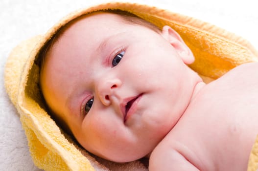 Sweet newborn baby wrapped in a towel and smiling, isolated against a white background.