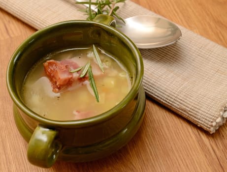 Green ceramic bowl with bean soup and bacon