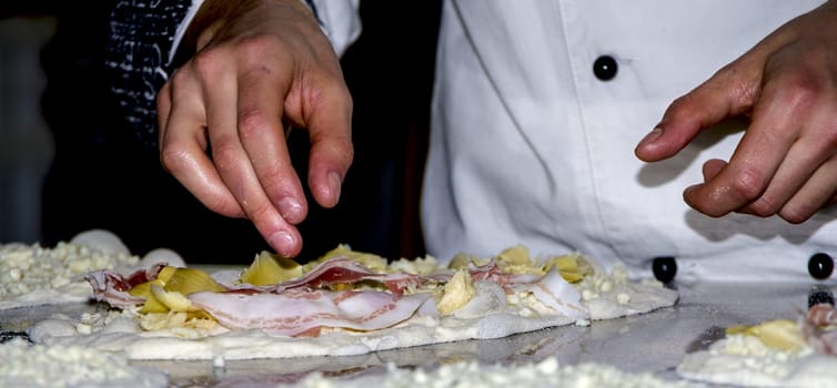 Preparing pizzas with mozzarella, bacon and artichokes for cooking