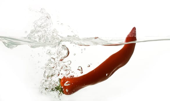 Red pepper splashing into water isolated on white