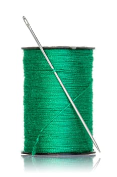 Spool of green thread with needle isolated on white background