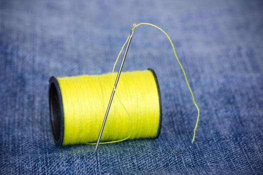Needle with yellow thread on jeans material