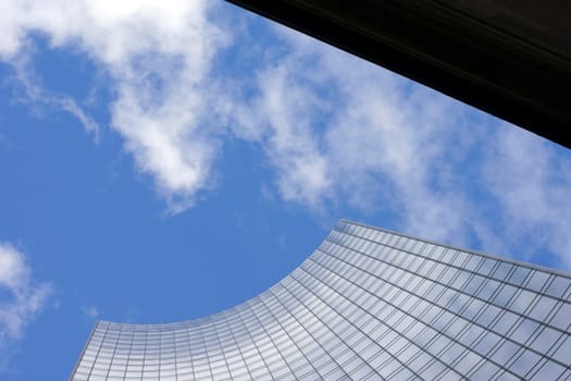 The photograph of a high-rise facade and a corner of the house against the sky.