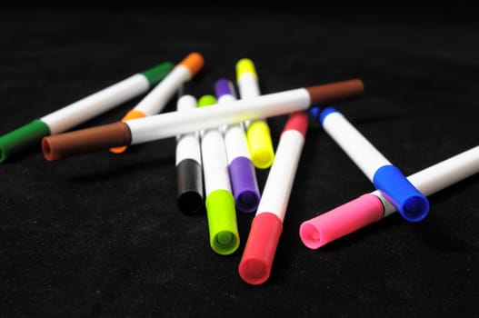 Some Colored Ink Markers on a Black Background