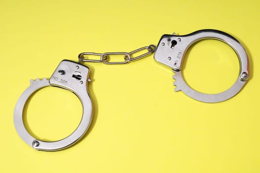 One Pair of Handcuffs on a Colored Background