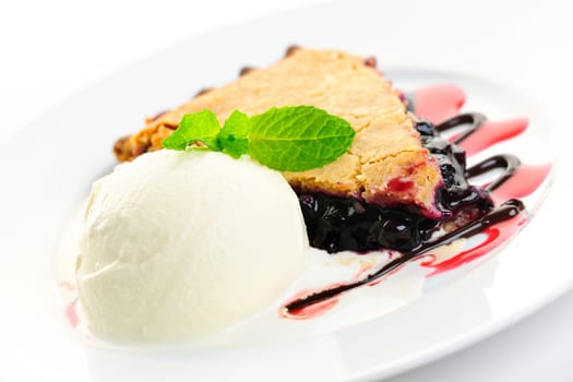 Slice of blueberry pie and vanilla ice cream served with dessert sauces