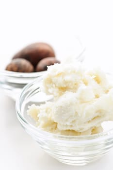 Shea butter and nuts in glass bowls isolated on white