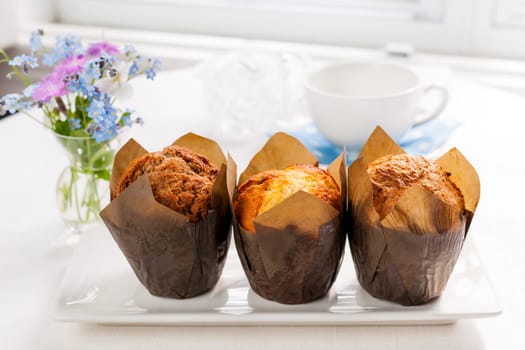 Breakfast table with three muffins in brown paper baking cups