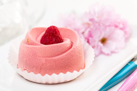 Closeup of pink raspberry mousse dessert with cherry blossom