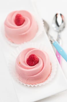 Two pink raspberry mousse desserts on a plate