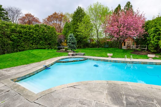 Backyard with outdoor inground residential private swimming pool and stone patio