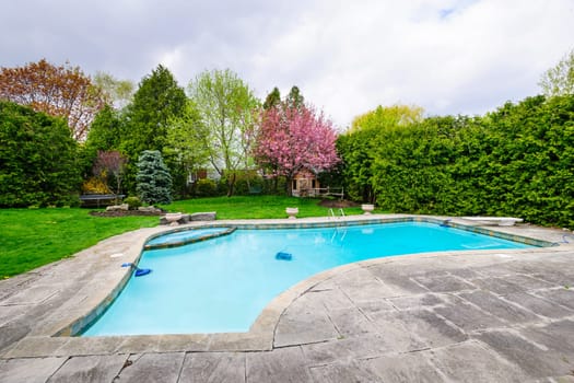 Backyard with outdoor inground residential private swimming pool and stone patio