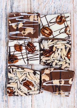Assorted chocolate caramel bark pieces for sweet dessert arranged on wooden background, top view