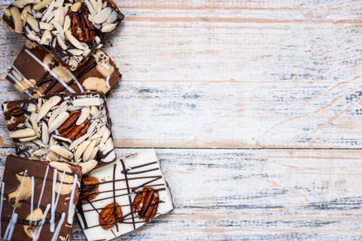 Assorted chocolate caramel bark pieces arranged on wooden background from above with copy space