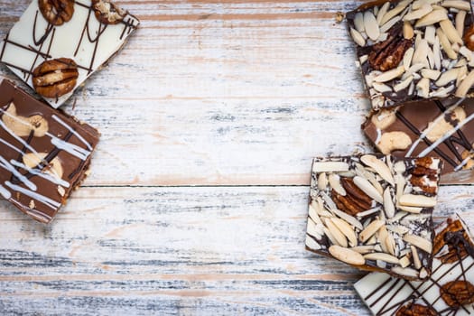 Assorted chocolate caramel bark pieces arranged on wooden background from above with copy space