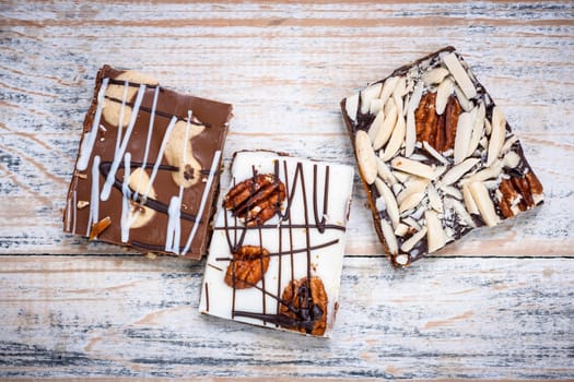 Three assorted chocolate caramel bark pieces as sweet dessert arranged on wooden background from above