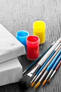 Various sizes of paintbrushes with blank canvas and paints