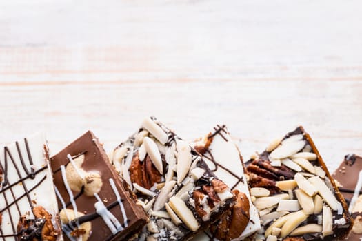 Assorted chocolate caramel bark pieces arranged on wooden background from above with copy space