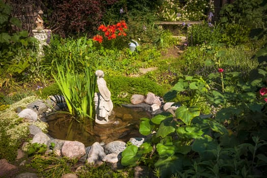 Statue in small pond of natural summer garden
