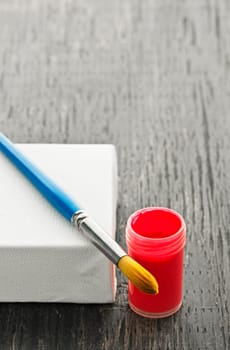 Paintbrush on white blank canvas with red paint