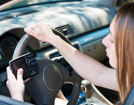 Teenage girl texting on cell phone while driving