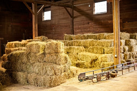 Interior of barn with hay bales stacks and conveyor belt