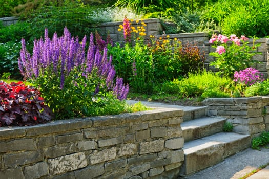 Natural stone landscaping in home garden with steps and flowerbeds