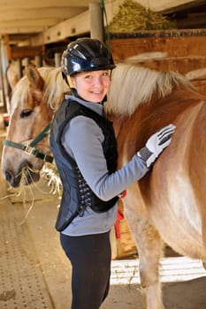 Portrait of teenage girl with horse in stable