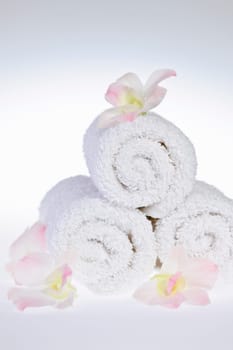 White rolled up spa towels with orchids flowers